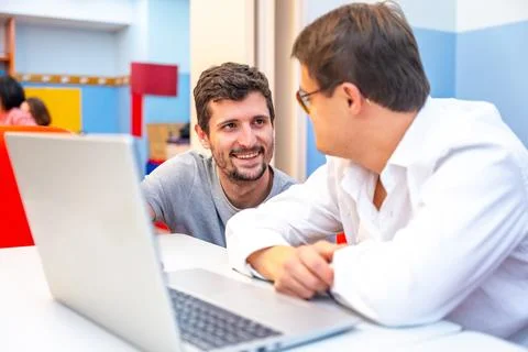Teacher talking to a disabled man during computing class Stock Photos