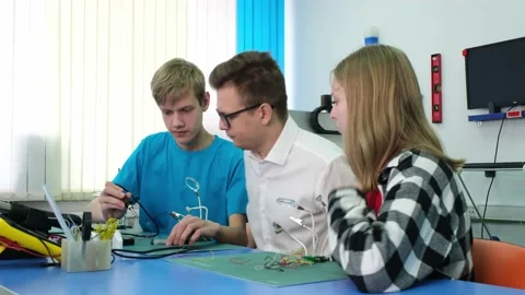 The teacher teaches the boy how to work with an electric soldering iron Vidéo 171291284