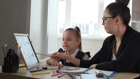 A teacher teaching child math numbers and how to count, sits at a table usi.. Stock Footage 273566927