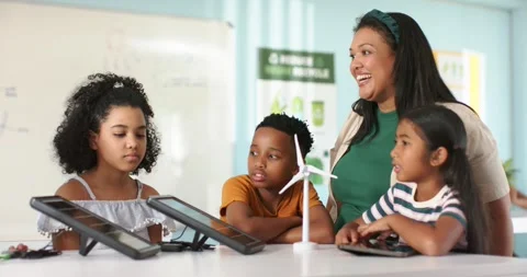 Teacher with teens watching offframe hand pointing at turbine and tablets at Stock Footage 345071408