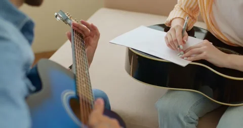 Teacher, tutor playing guitar while student writing notes on exercises book 스톡 동영상 255354355
