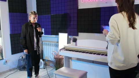 Teacher uses tablet standing in front of student with microphone Stock Footage 307037716