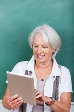 Teacher using digital tablet against chalkboard Stock Photos