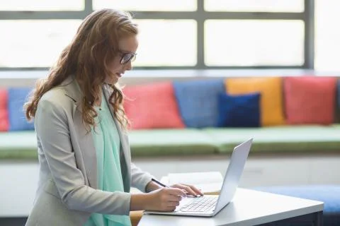 Teacher using laptop in library Stock Photos