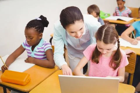 Teacher using laptop with pupil Stock Photos