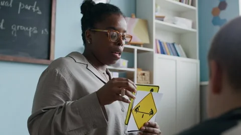 Teacher Using Visual Aids to Teach Young Students Traffic Symbols Stock Footage 312053876