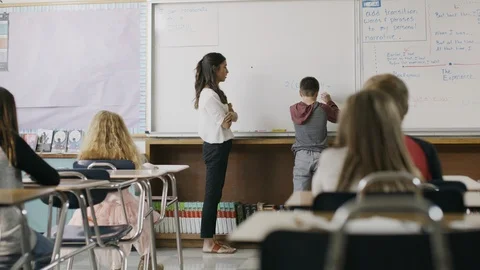 Teacher watching boy solving math equation on classroom whiteboard ,Provo, Utah, Stock Footage 85911652