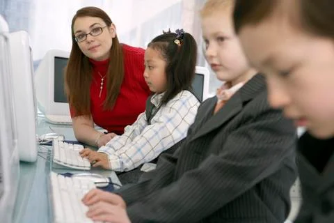 Teacher Watching Children Using Computers Stock Photos