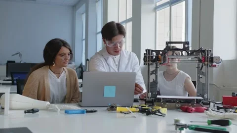 Teacher in white goggles shows how to use and how to work with the 3D printer Stock Footage 157515320