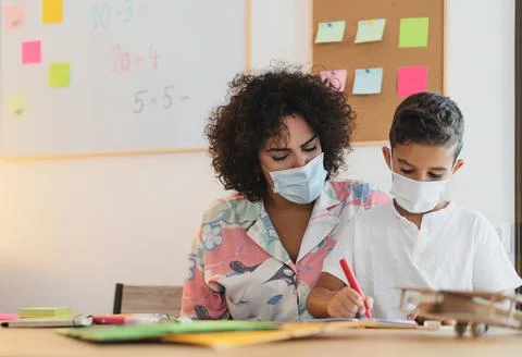 Teacher woman with child wearing face protective mask in preschool classroom Stock Photos