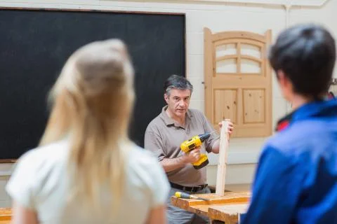 Teacher of a woodwork class teaching two students Stock Photos