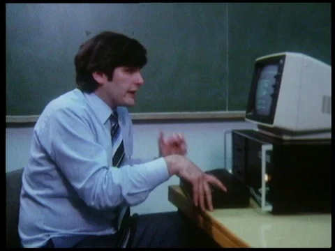 Teacher working with computer, two men with masks standing still, 1985 Stock Footage 136676958
