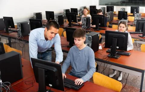 Teacher working with student at computer class Stock Photos