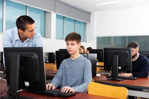 Teacher working with student at computer class Stock Photos