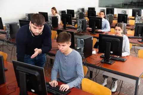 Teacher working with student at computer class Stock Photos