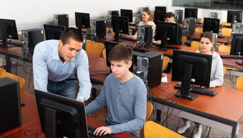 Teacher working with student at computer class Stock Photos