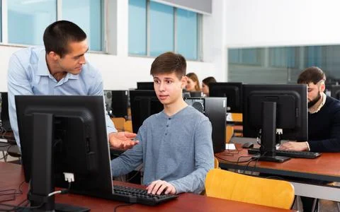 Teacher working with student at computer class Stock Photos