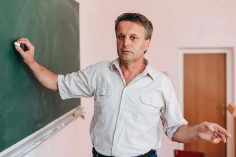 Teacher write on the blackboard and explain a lesson.- Image Stock Photos