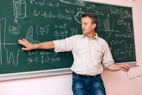 Teacher write on the blackboard and explain a lesson.- Image Stock Photos