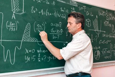Teacher write on the blackboard and explain a lesson.- Image Stock Photos