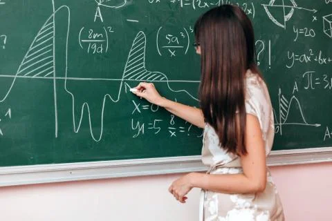 Teacher write an example on the blackboard and explain a lesson.- Image Stock Photos