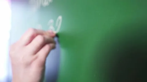 The teacher writes a math example on the school board. Math lesson. Stock-Footage 135871911