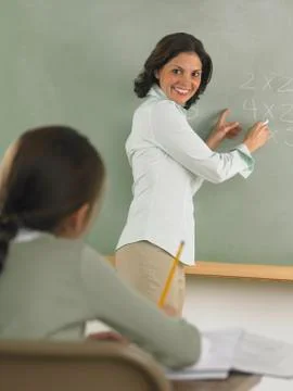 Teacher writing arithmetic on the blackboard Stock Photos