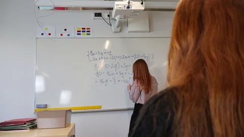 Teacher writing complex math equations on whiteboard with student learning Stock Photos