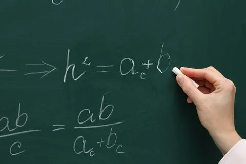 Teacher writing down math equation on green board, closeup Stock Photos