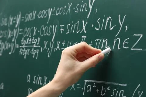 Teacher writing down math equation on green board, closeup Stock Photos
