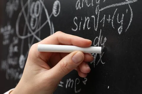 Teacher writing math formulas with chalk on blackboard, closeup Stock Photos