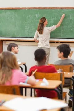 Teacher writing math problems on blackboard Stock Photos