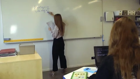 Teacher writing mathematics equations while student uses AI Видео 345187749