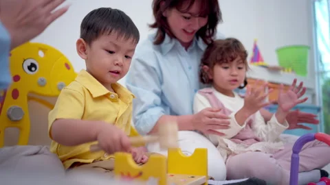 Teachers and parent playing joyfully with children, enhancing social 動画素材 339583754