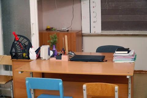 Teacher's desk with a laptop and a stack of papers in the classroom in front of Stock-Fotos