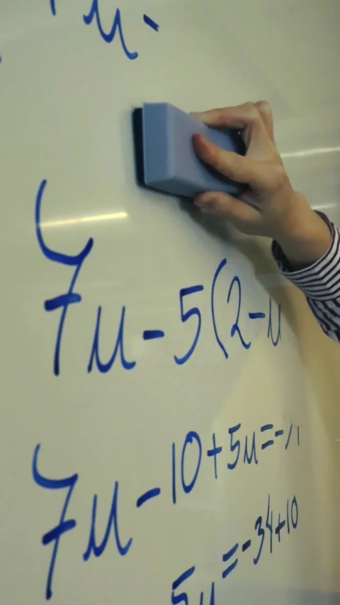 Teacher's hand erasing mathematics equations from a whiteboard Stock Footage 345550821