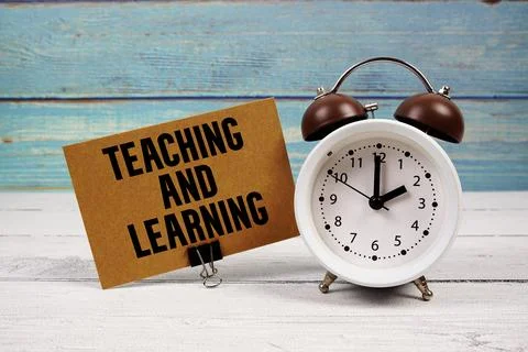 Teaching and Learning text written on paper card with alarm clock on wooden back Stock Photos