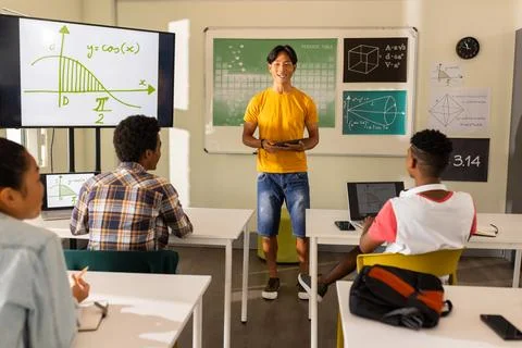 Teaching math, teacher using tablet in classroom with students at high school Stock Photos