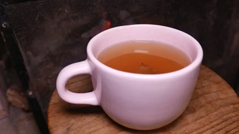 Teacup by the fireplace. A cup of ginger tea with honey. Cup of tea on a table Stock Footage 346652412