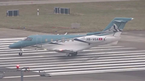Teal and white pilatus pc 24 light private jet crosses bold runway threshold Stock Footage 328125581