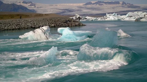 Teal ice pieces stuck in riverbed seem to lean against river water. Stock Footage 123636006