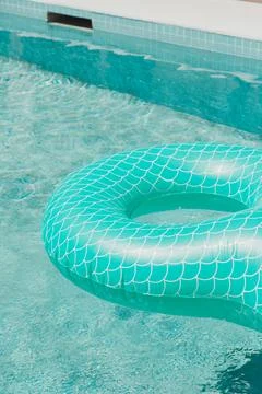 Teal mermaid-scale float ring in clear swimming pool Stock Photos