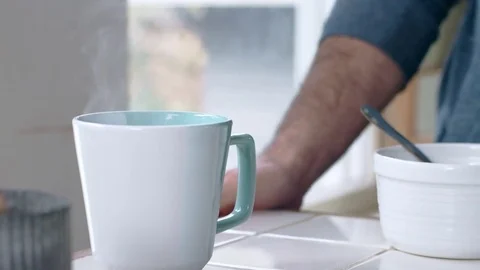 Teal mug filled with steaming hot water with hispanic man in background Stock Footage 84473790