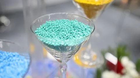 Teal plastic masterbatch pellets displayed in a glass Stock Photos