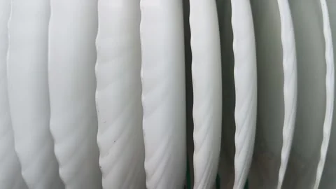 A teal wire basket filled with several white, scalloped-edge plates. Видео 329217620