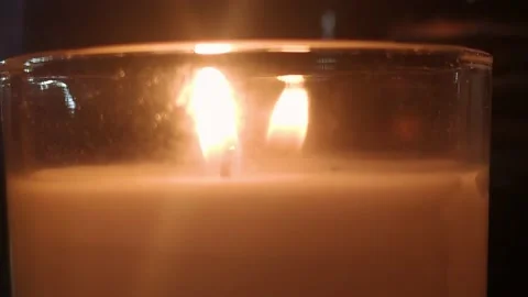 Tealight candle set on fire. Single candle flame on horizontal black background Stock Footage 217764466