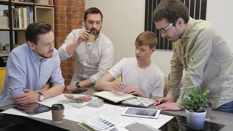 Team of 4 men to brainstorm creative office. Young guys gathered around the Stock Footage 78158952
