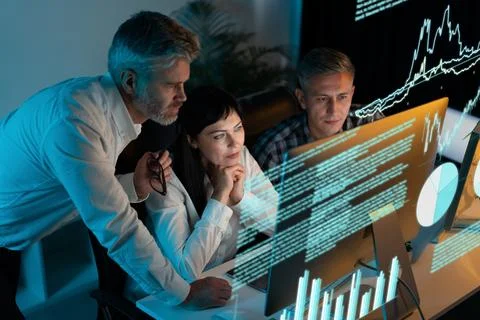 Team Analyzing Data on Computer Screens in Office Environment Foto stock