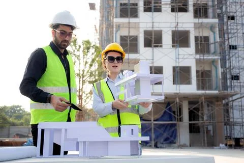 Team architect and builder talking and holding model house at construction .. Stock Photos