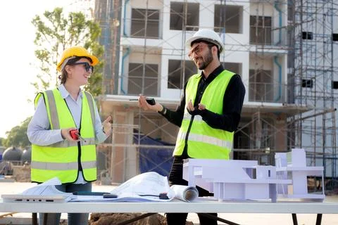 Team architect and builder talking and holding model house at construction .. 写真素材